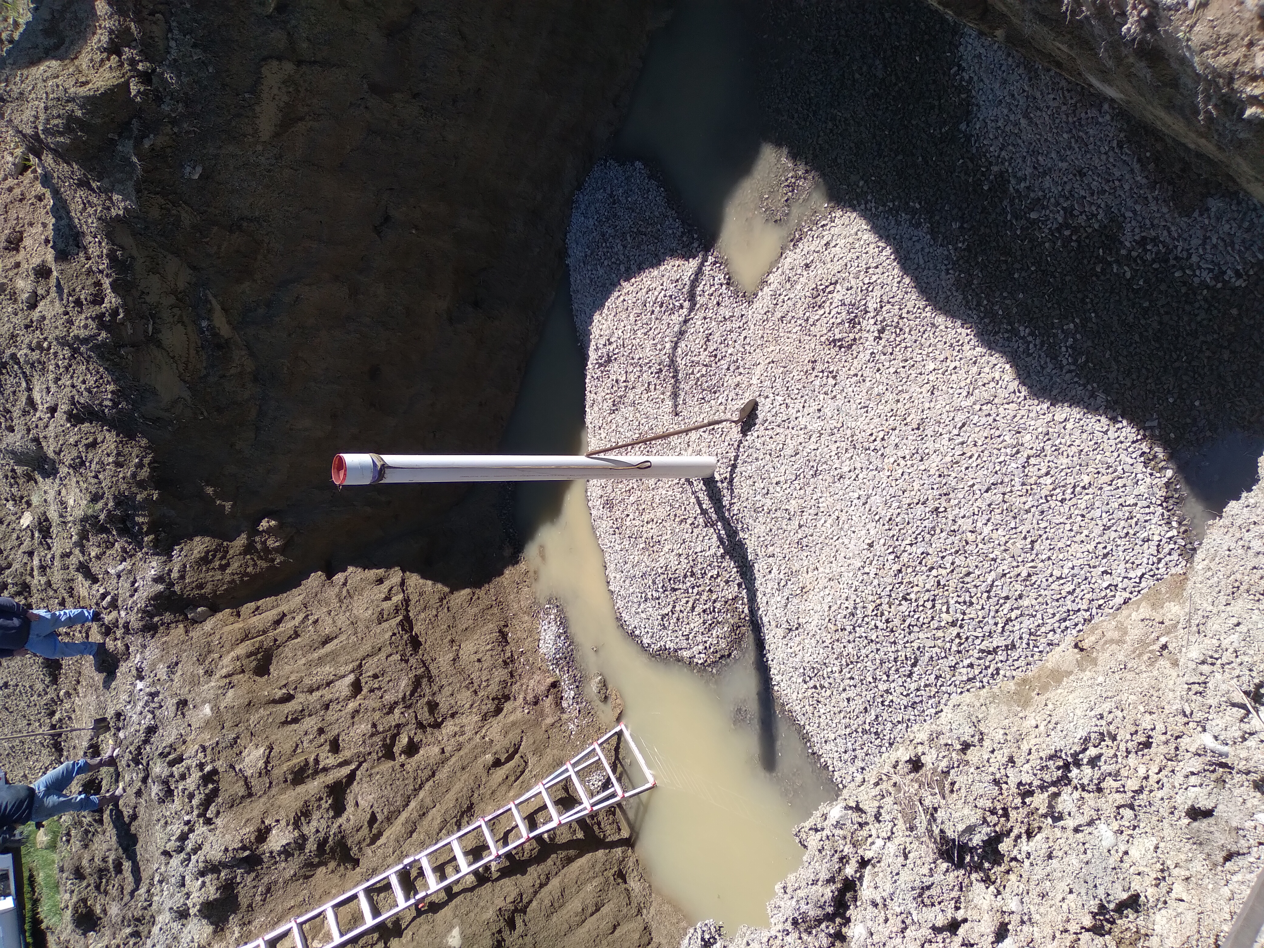 Hole dug for well with well pipe installed and gravel being added. Photo credit Andrew Toothacker