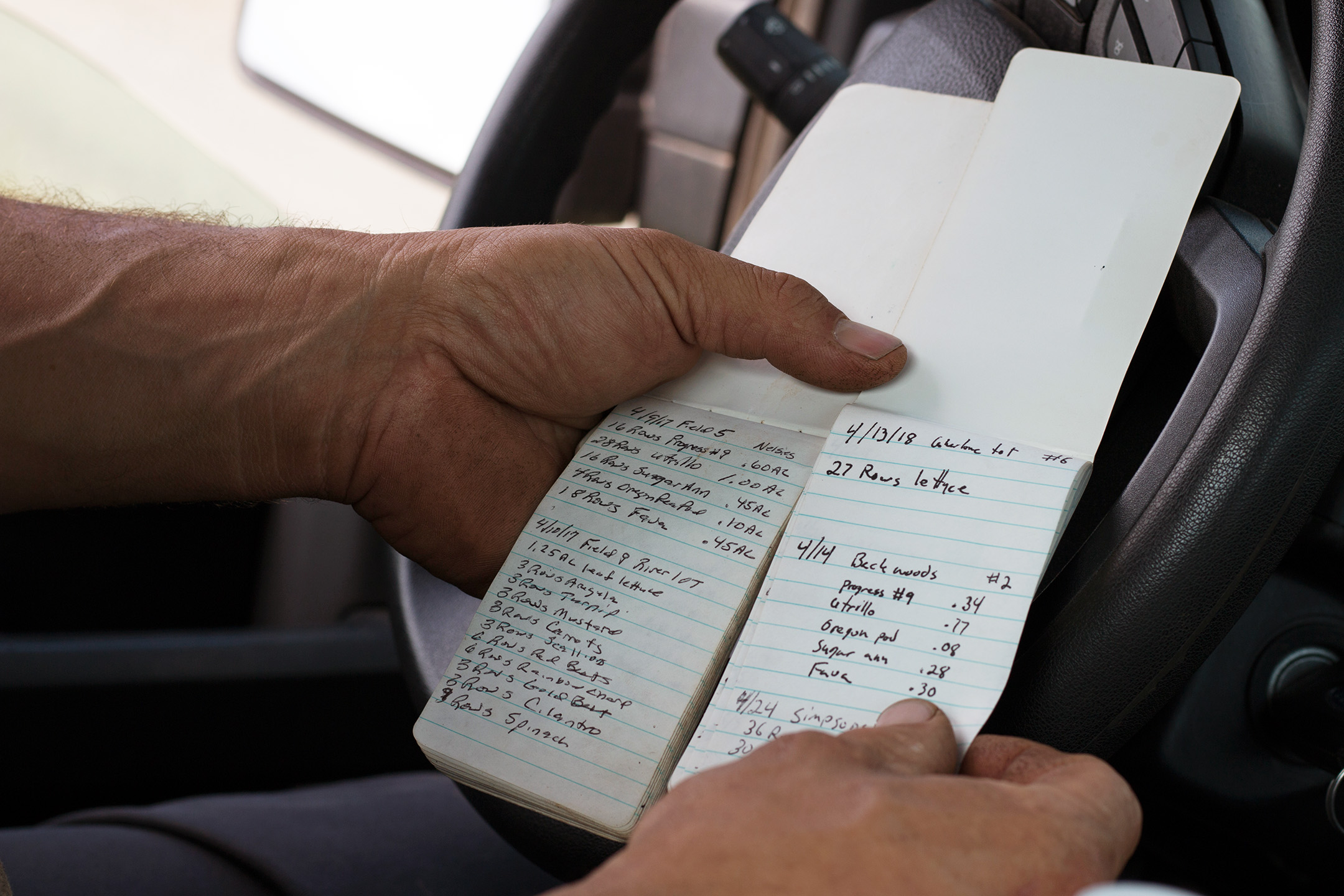 William DellaCamera compares annual planting notes. The notebook on the left was logged by Nelson Cecarelli last year, while the notebook on the right is from the current 2018 season