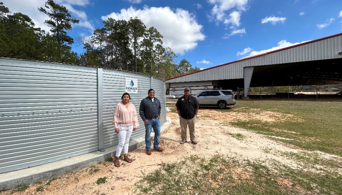 3 tribal members standing in front of a 65,000 gal rainwater harvesting tank.