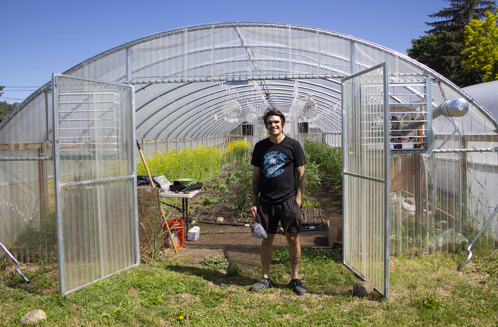 An image of Brandon Gerard, owner of Peak of Abundance, standing in front of his high tunnel. 