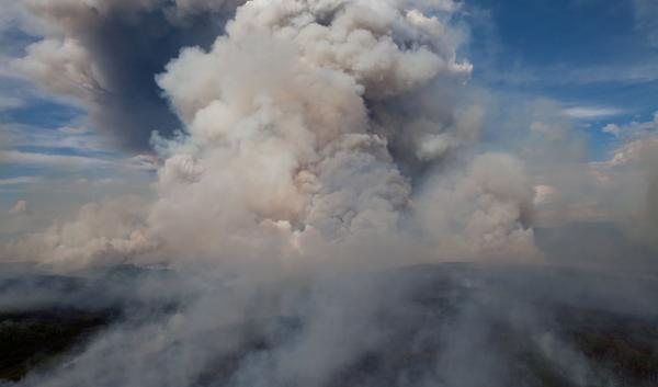 A smoke column rises from the Alaskan forests