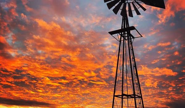 A windmill is silhouetted against a magnificent New Mexico Sunset. 